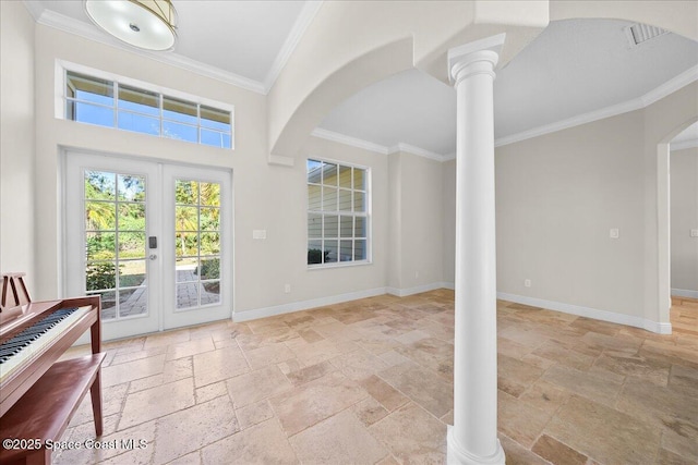 entrance foyer featuring stone tile floors, crown molding, decorative columns, and baseboards