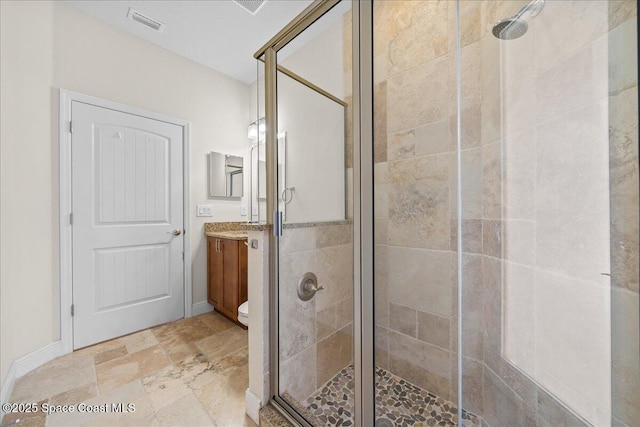 bathroom with stone finish floor, a stall shower, vanity, and visible vents