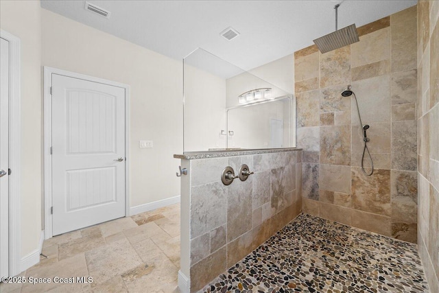 bathroom with tiled shower, visible vents, and stone tile floors