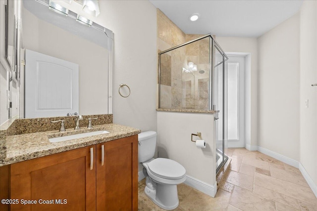 full bath with a stall shower, baseboards, vanity, and toilet