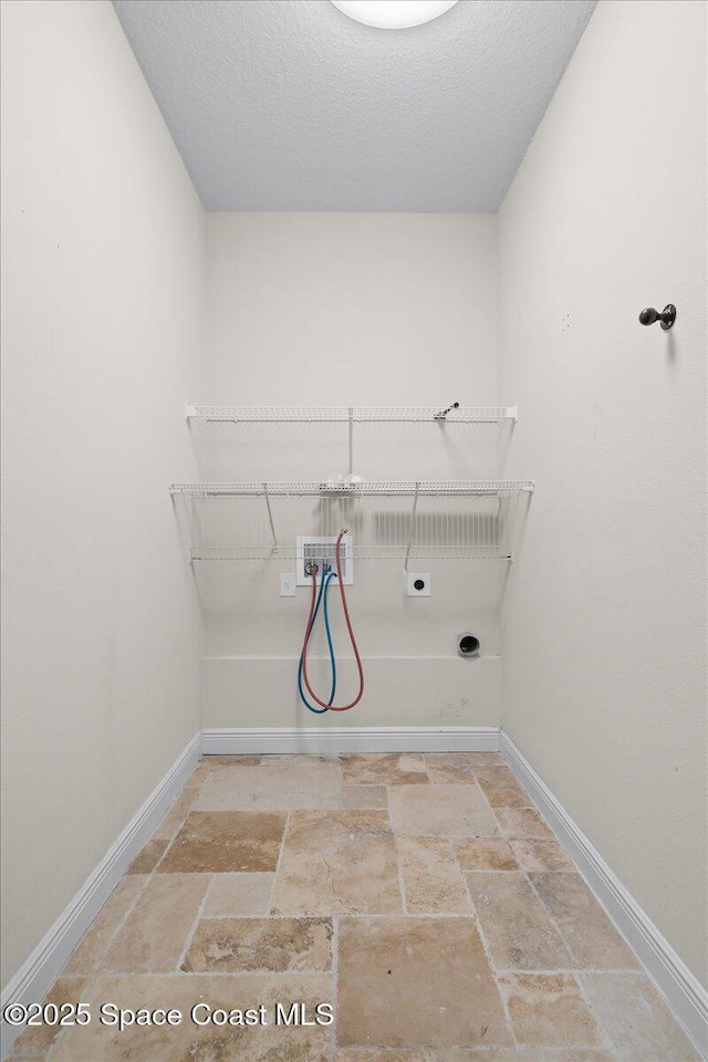 washroom featuring stone tile floors, hookup for an electric dryer, laundry area, washer hookup, and baseboards