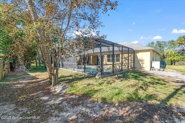 back of house featuring glass enclosure, an outdoor pool, and a lawn