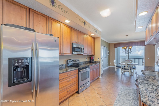 kitchen featuring light tile patterned floors, a sink, appliances with stainless steel finishes, brown cabinetry, and crown molding