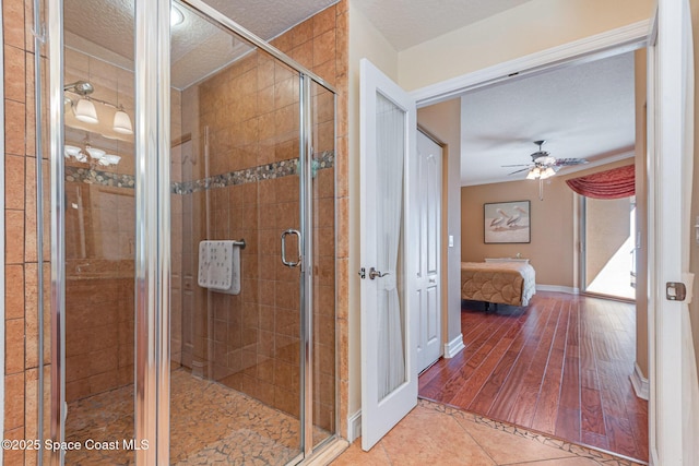 ensuite bathroom with a ceiling fan, ensuite bath, tile patterned flooring, a textured ceiling, and a shower stall