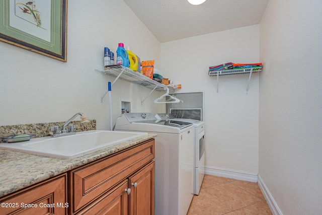 laundry area featuring cabinet space, baseboards, washer and dryer, a sink, and light tile patterned flooring