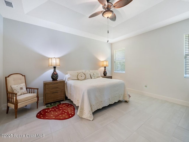 bedroom with light tile patterned floors, a ceiling fan, visible vents, baseboards, and a raised ceiling