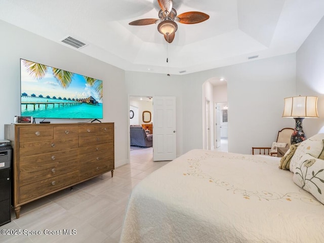 bedroom with arched walkways, visible vents, a tray ceiling, and light tile patterned floors