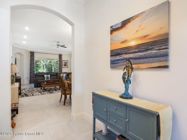 corridor with arched walkways, crown molding, baseboards, and recessed lighting