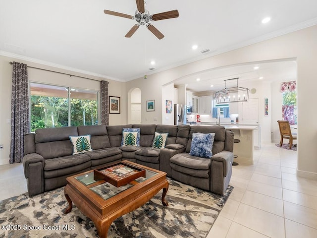 living room featuring arched walkways, crown molding, recessed lighting, and light tile patterned floors