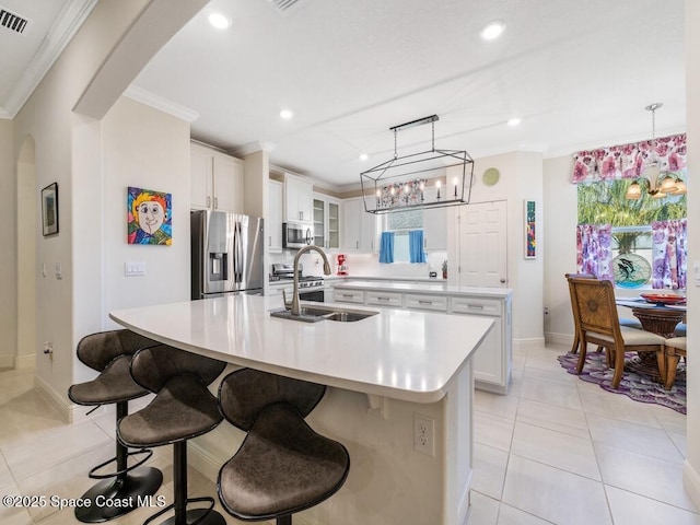 kitchen featuring arched walkways, a large island, stainless steel appliances, crown molding, and a sink