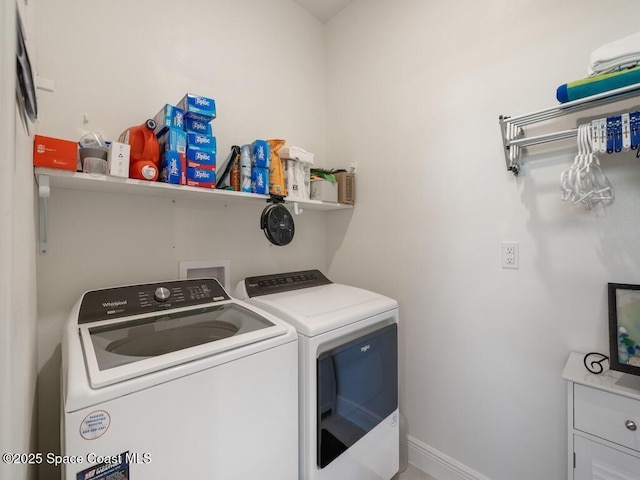 clothes washing area with baseboards, laundry area, and washer and dryer