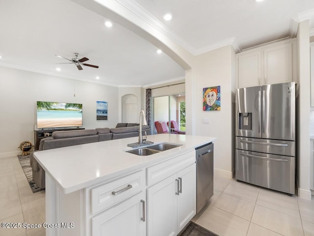 kitchen featuring arched walkways, crown molding, light countertops, appliances with stainless steel finishes, and a sink