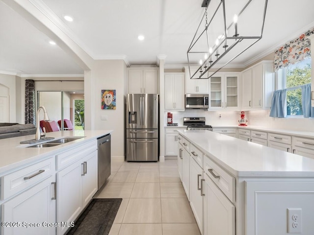 kitchen with a center island with sink, decorative backsplash, ornamental molding, stainless steel appliances, and a sink