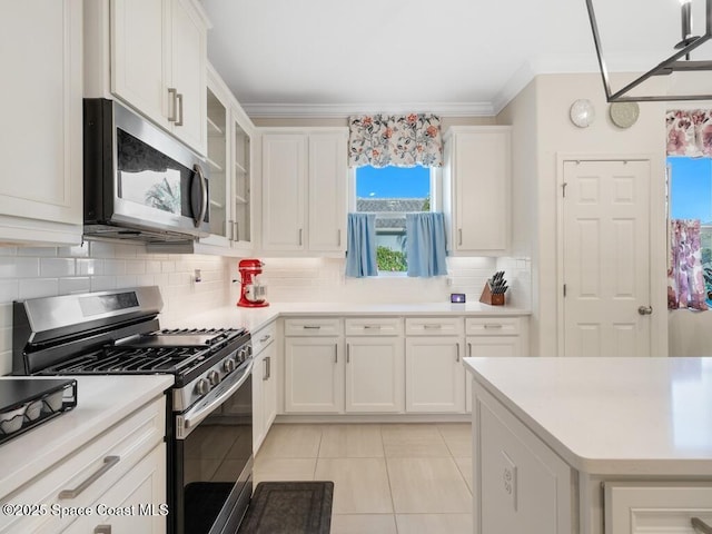 kitchen featuring stainless steel appliances, white cabinetry, light countertops, ornamental molding, and decorative backsplash