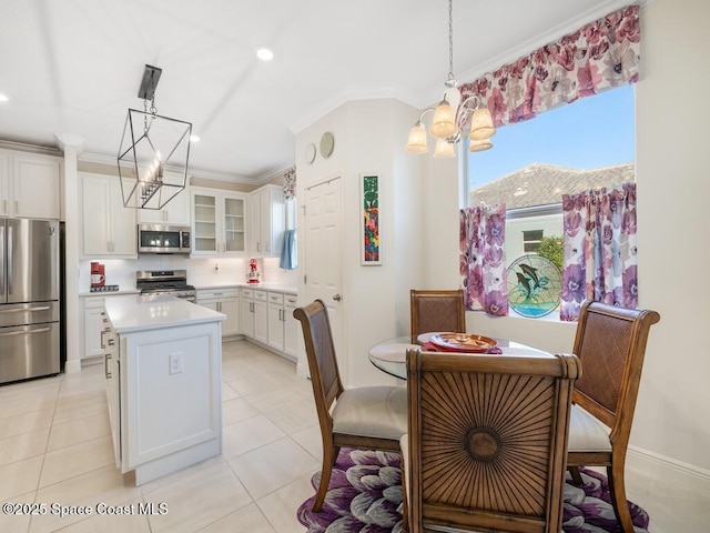 kitchen featuring a kitchen island, ornamental molding, stainless steel appliances, light countertops, and a chandelier