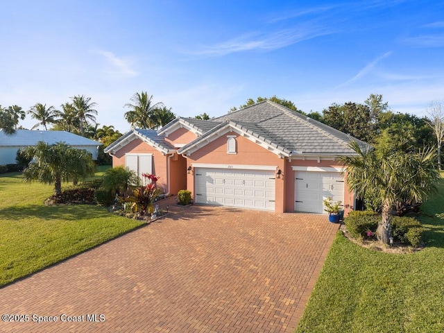 ranch-style home featuring decorative driveway, stucco siding, a garage, a tiled roof, and a front lawn