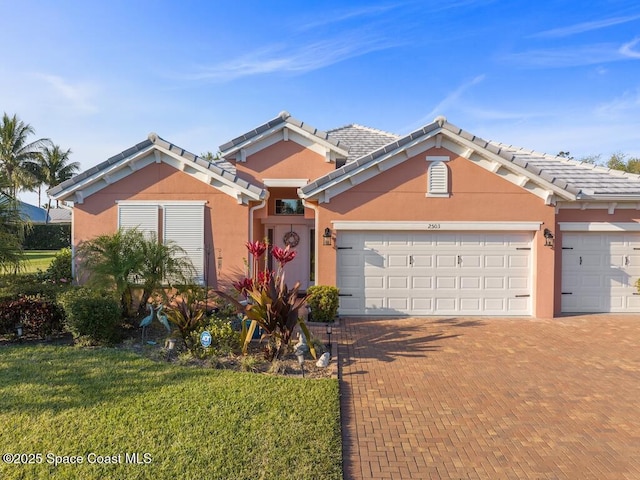 view of front facade featuring a garage, decorative driveway, a tiled roof, and stucco siding