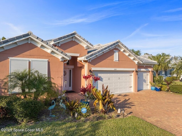 view of front of property with a garage, decorative driveway, a tile roof, and stucco siding