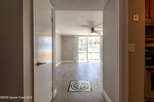 corridor with light tile patterned floors, baseboards, ornamental molding, floor to ceiling windows, and a textured ceiling