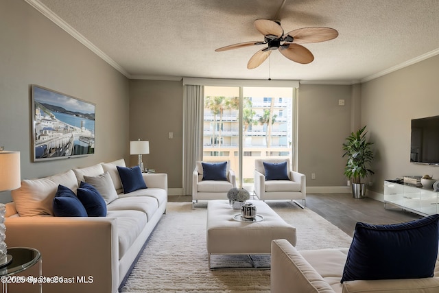 living area featuring ceiling fan, baseboards, a textured ceiling, and ornamental molding