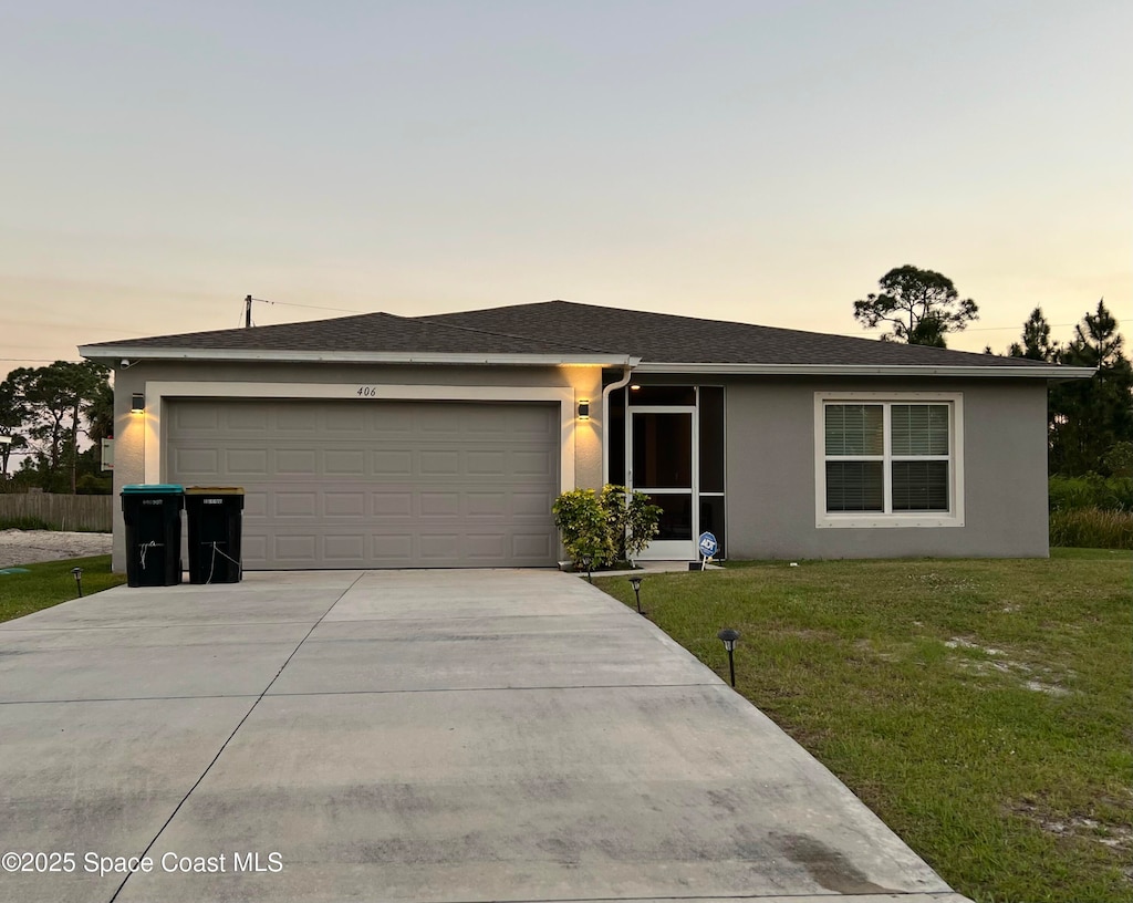 ranch-style home featuring stucco siding, driveway, an attached garage, and a front lawn