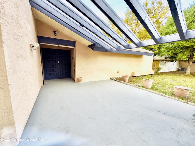 view of exterior entry featuring a patio area, a yard, fence, and stucco siding