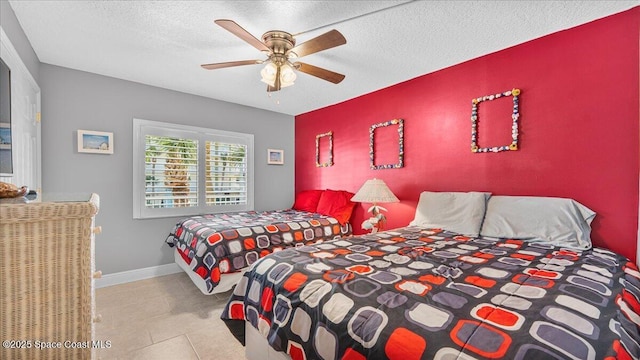 bedroom featuring a ceiling fan, an accent wall, baseboards, and a textured ceiling