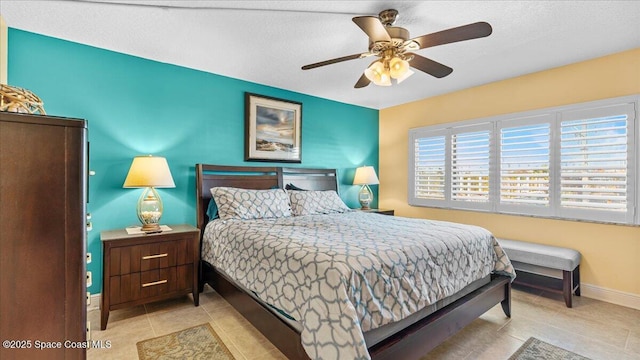 tiled bedroom with ceiling fan and baseboards