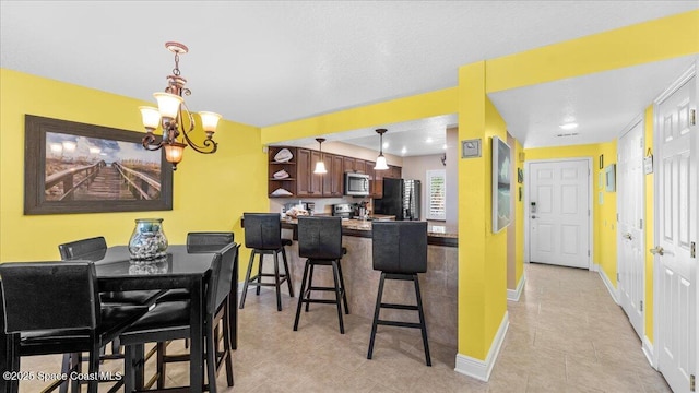 kitchen featuring open shelves, stainless steel appliances, a kitchen bar, an inviting chandelier, and baseboards