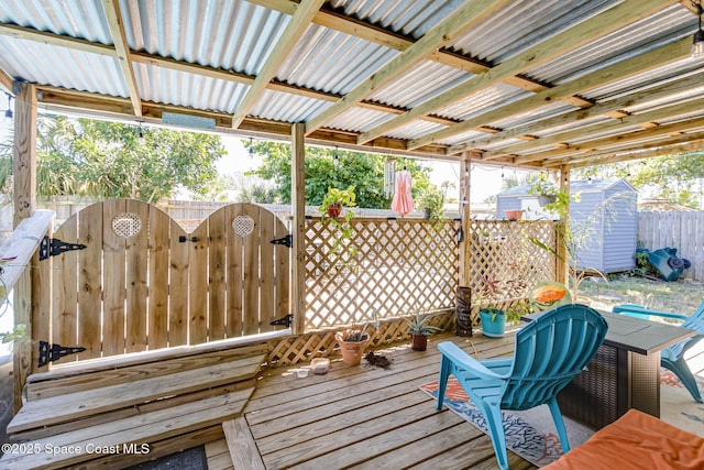 wooden terrace featuring fence, a storage shed, an outdoor structure, and a gate