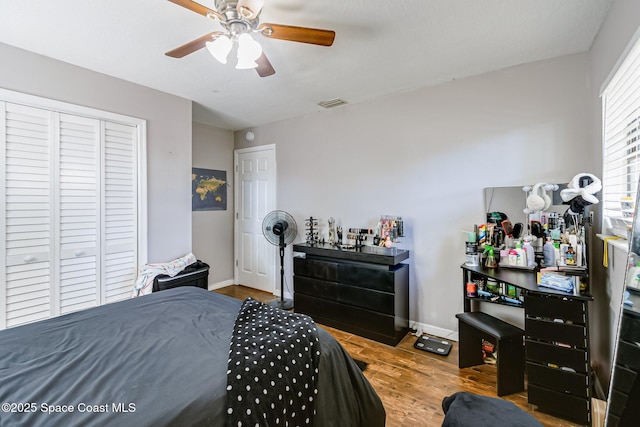 bedroom with visible vents, a ceiling fan, wood finished floors, a closet, and baseboards