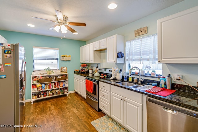 kitchen with a wealth of natural light, dark wood-type flooring, a sink, appliances with stainless steel finishes, and white cabinets