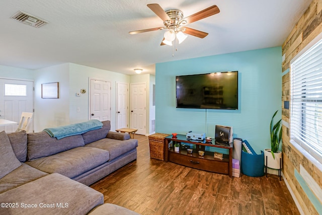 living room with ceiling fan, visible vents, plenty of natural light, and wood finished floors