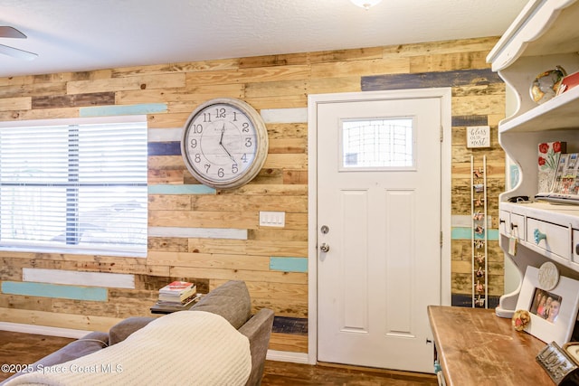 interior space featuring baseboards, wood walls, and a ceiling fan