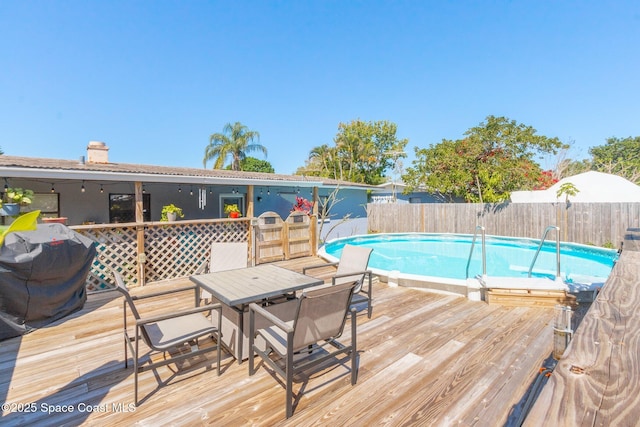 view of swimming pool featuring outdoor dining area, a fenced in pool, fence, and a wooden deck