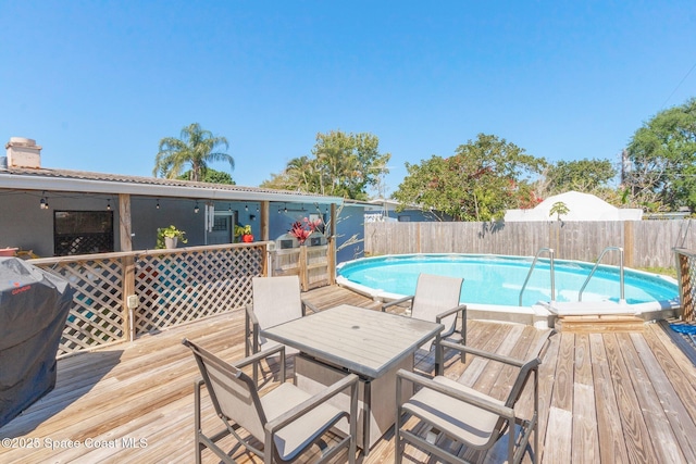 view of pool with area for grilling, a fenced in pool, fence, and a wooden deck