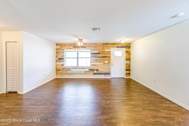 718 6th St, Merritt Island, FL 32953 - unfurnished living room with baseboards, dark wood-type flooring, wooden walls, and a ceiling fan