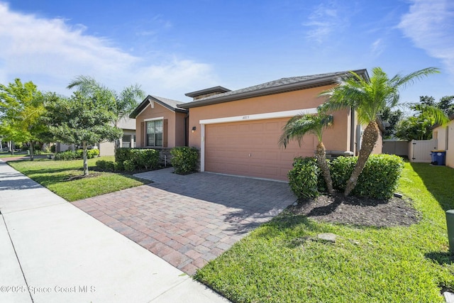 view of front of house with an attached garage, a front yard, decorative driveway, and stucco siding