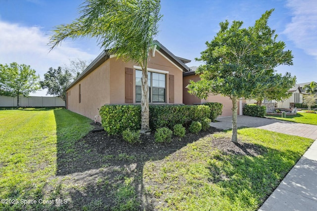 view of home's exterior featuring decorative driveway, an attached garage, a lawn, and stucco siding