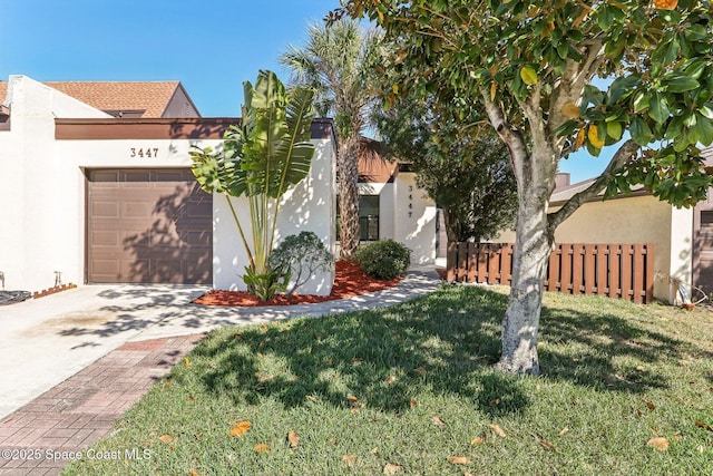 view of front of home featuring fence, driveway, stucco siding, a front lawn, and a garage