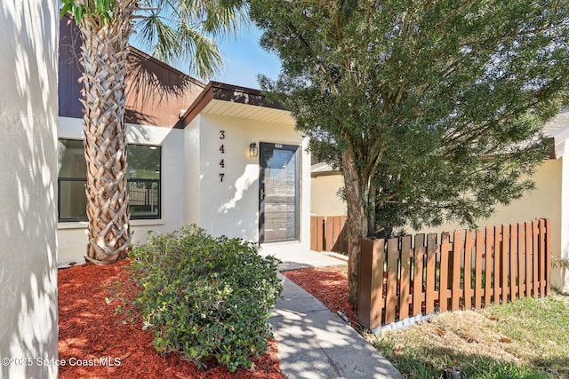 property entrance with fence and stucco siding