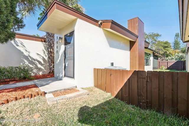 back of property featuring stucco siding, a chimney, and fence