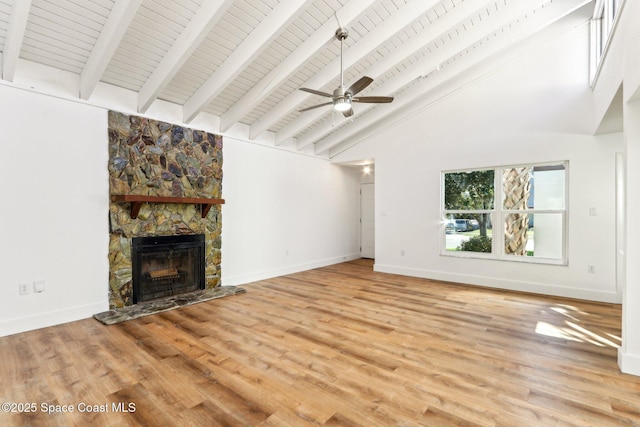 unfurnished living room featuring ceiling fan, baseboards, a stone fireplace, and wood finished floors