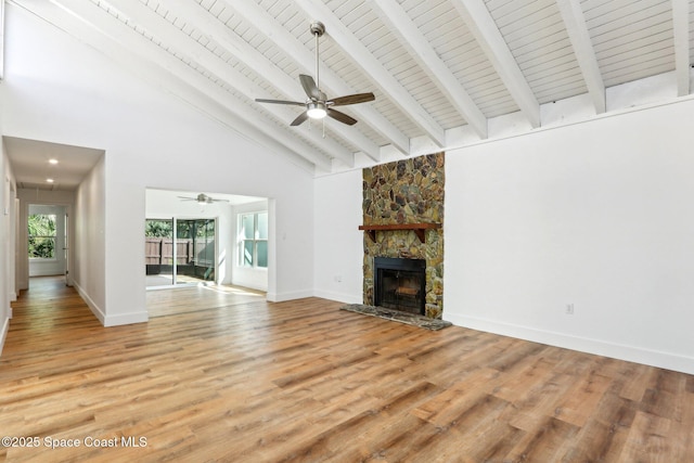 unfurnished living room with baseboards, beamed ceiling, light wood-type flooring, a fireplace, and a ceiling fan