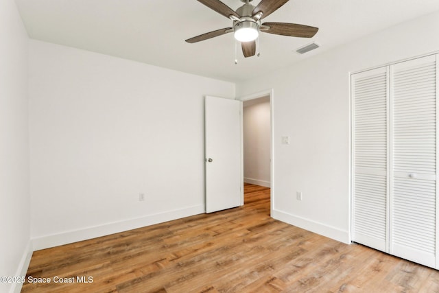 unfurnished bedroom featuring a ceiling fan, baseboards, visible vents, light wood-style flooring, and a closet