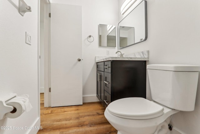 bathroom with toilet, vanity, baseboards, and wood finished floors