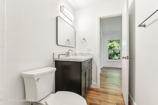 bathroom featuring toilet, vanity, baseboards, and wood finished floors