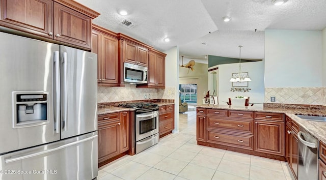 kitchen with light stone countertops, light tile patterned floors, appliances with stainless steel finishes, and vaulted ceiling