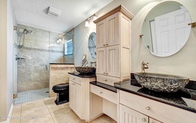 bathroom featuring tile patterned floors, a shower stall, a textured ceiling, and vanity