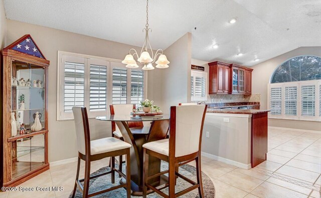 dining room featuring light tile patterned floors, vaulted ceiling, a textured ceiling, a chandelier, and baseboards